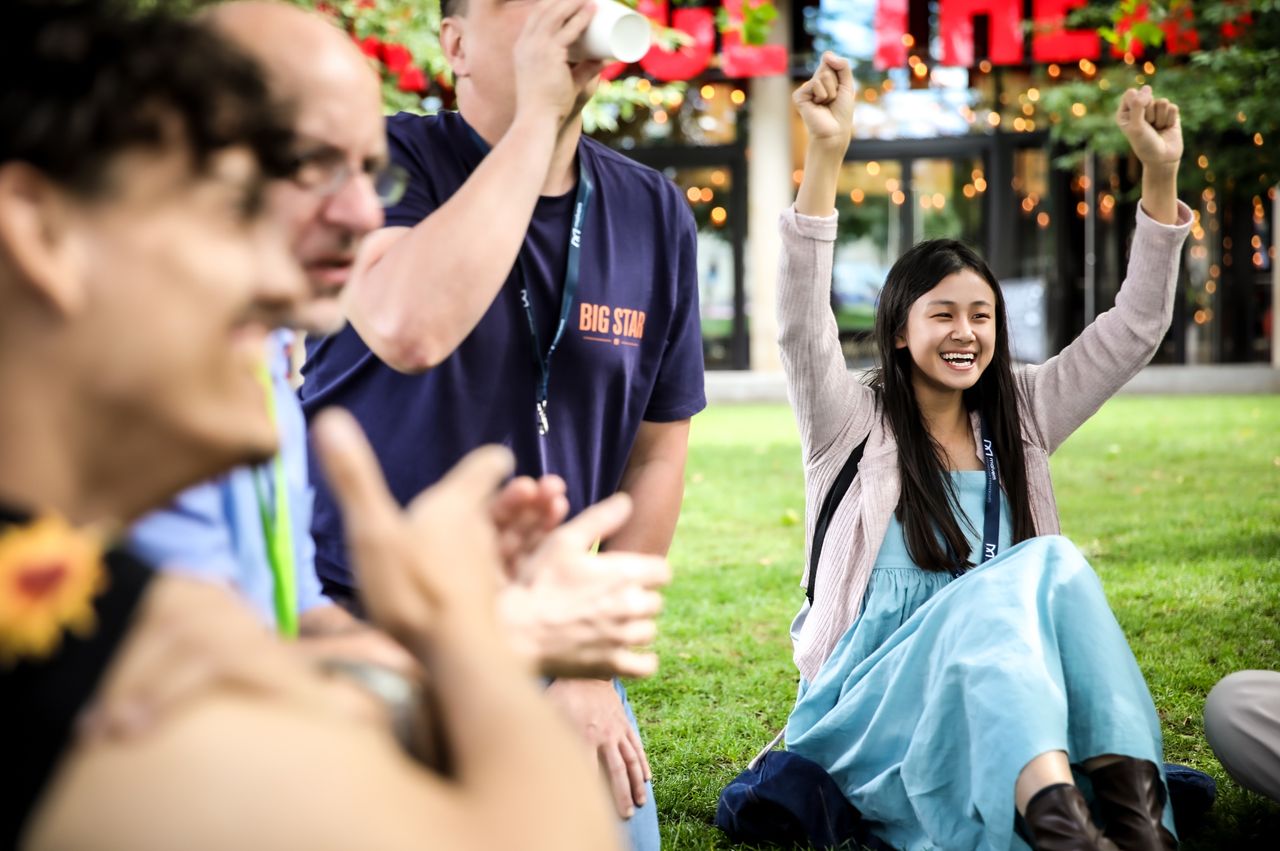young people smiling sitting on grass