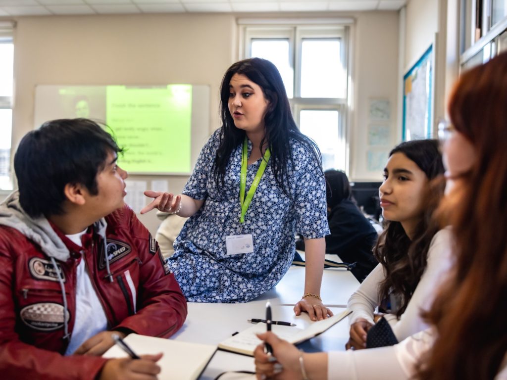 teacher with group of students at a desk